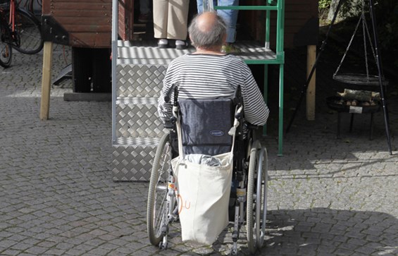 Person i rullstol framför en trappa.